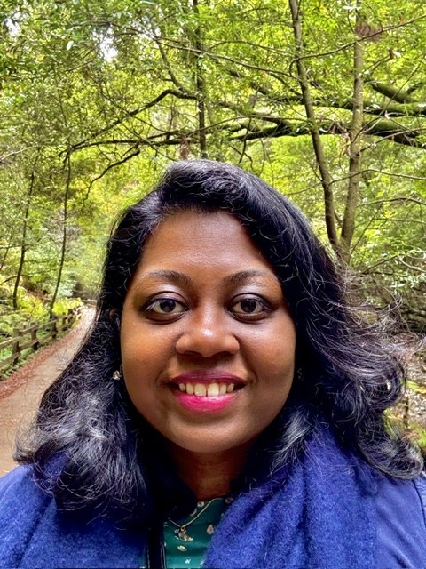 Abitha William smiling on a wooded trail